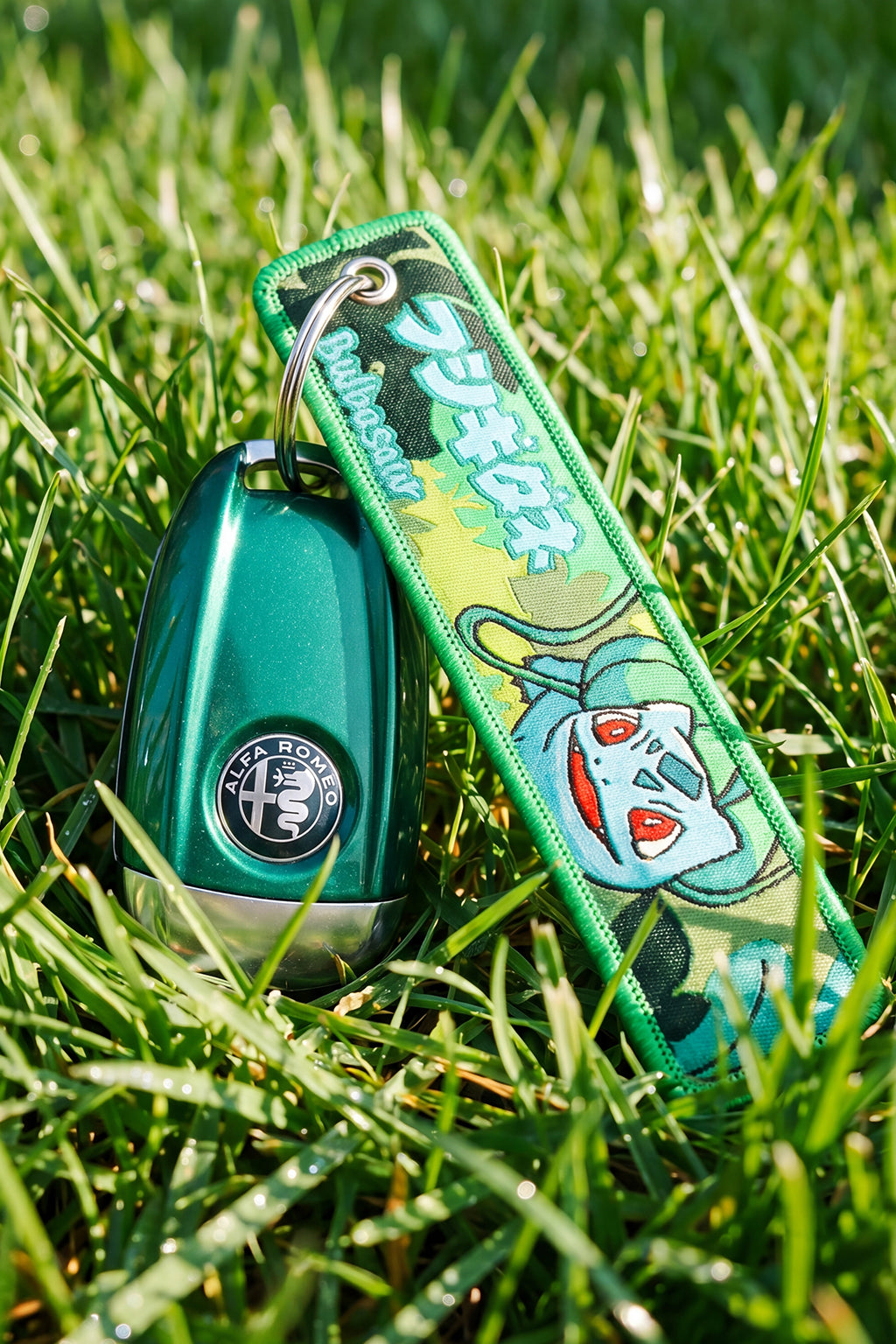 Green car key fob with a colorful strap on grass