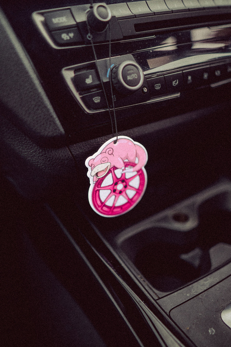 Pink car air freshener hanging from a car's dashboard