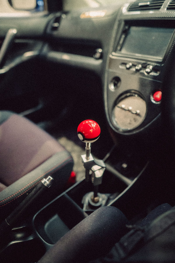 Car interior with a gear shift featuring a red and black ball design.