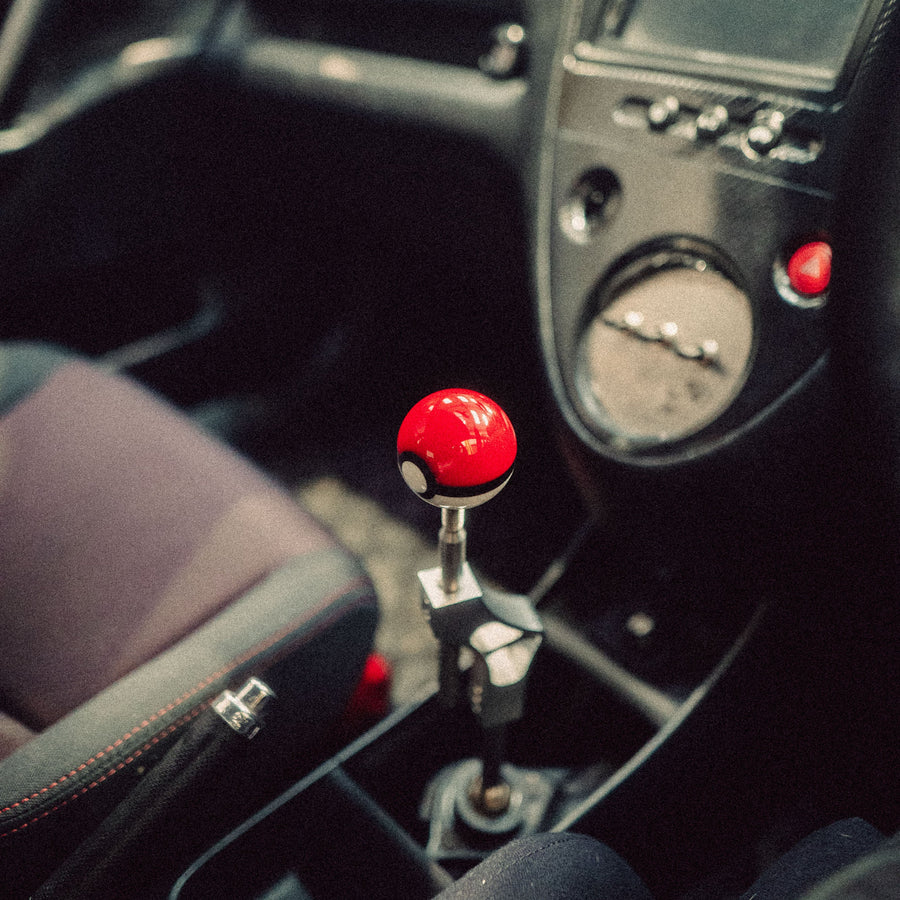Car interior with a gear shift featuring a red and black ball design.