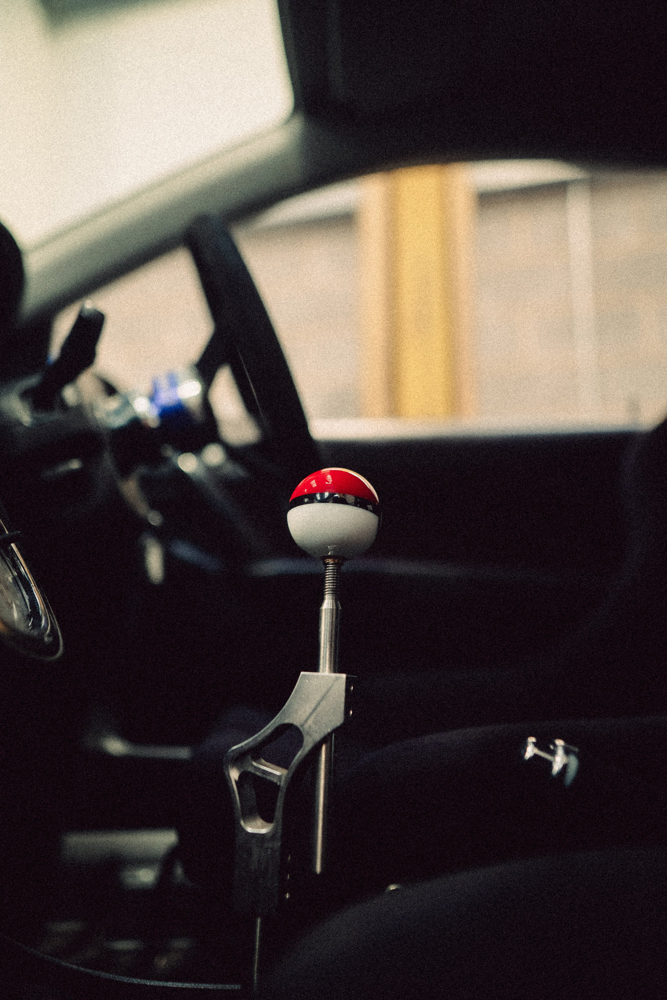 Car gear shift with a red and white top in a vehicle interior.