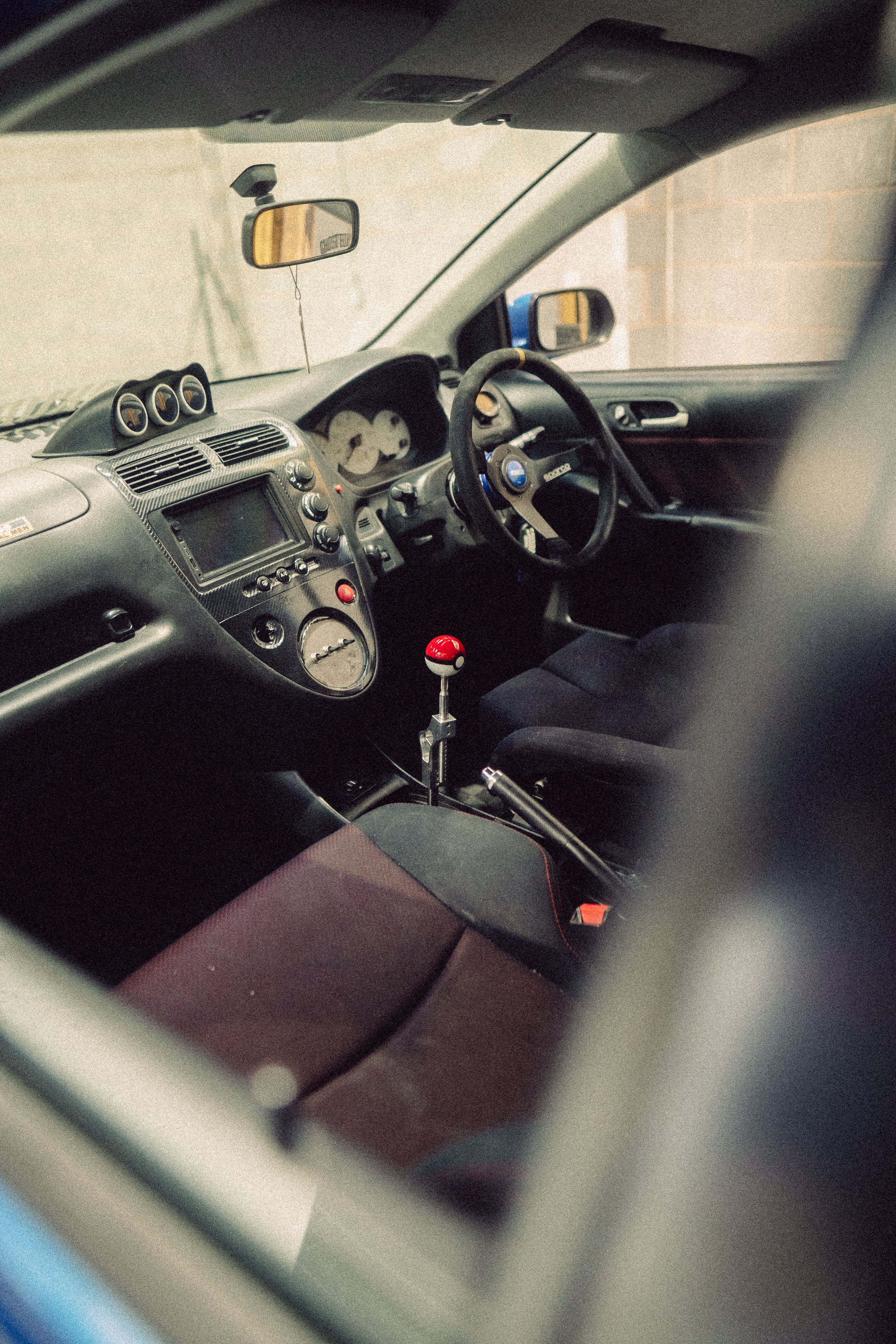 Car interior with a gear shift featuring a red and black ball design.