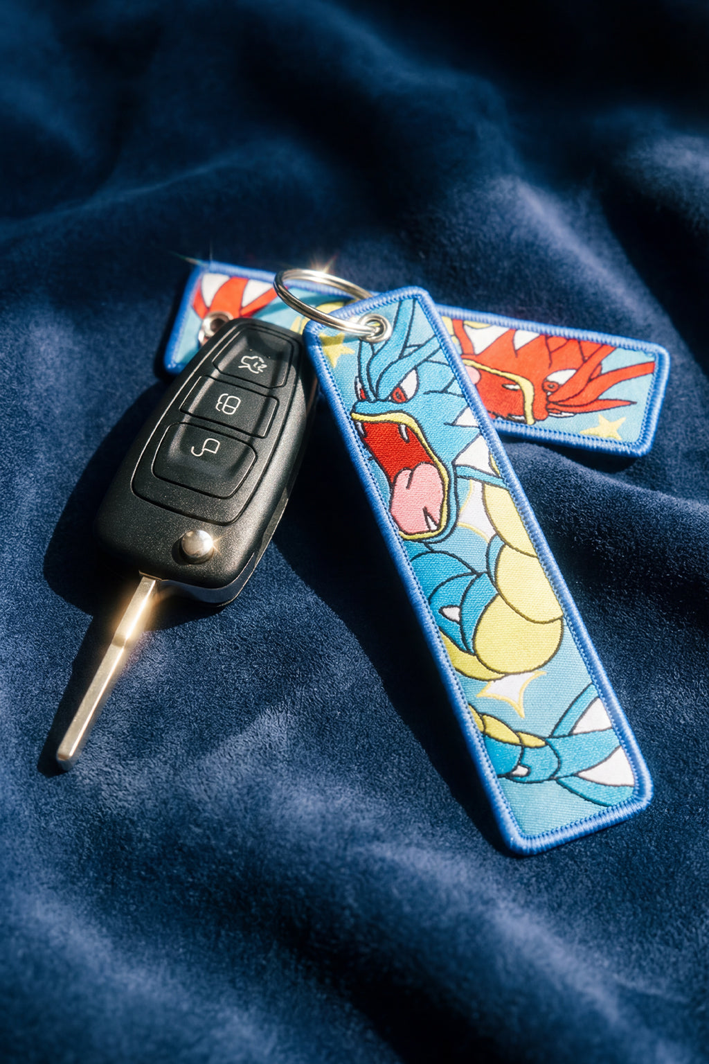 Keychain with cartoon design attached to a car key on a blue fabric background