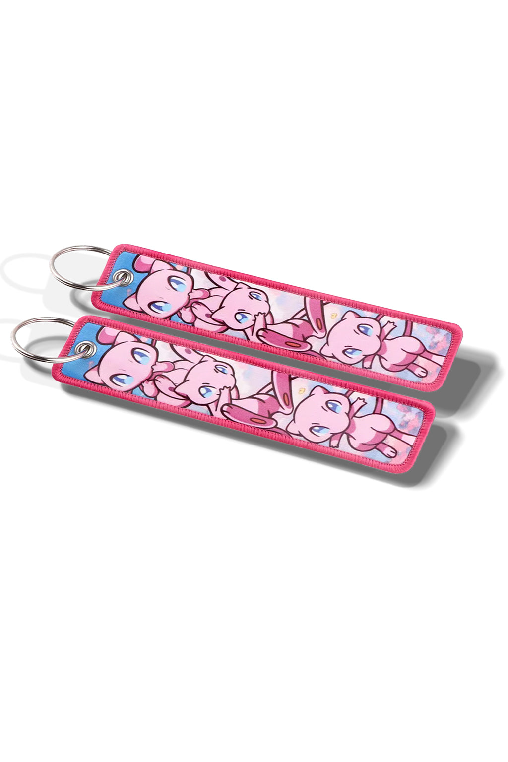 Keychain with cartoon mew design attached to a car key on a pink fabric background