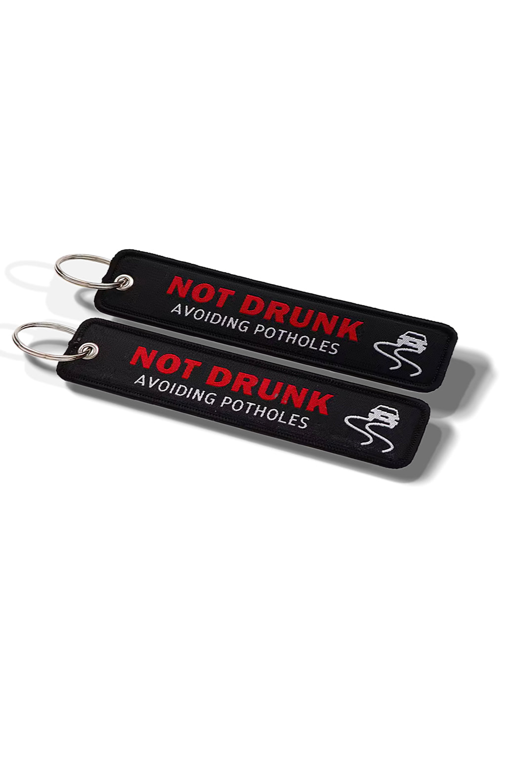 Keychain with 'Not Drunk Avoiding Potholes' text on a car seat.