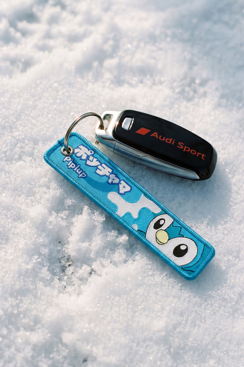 Keychain with cartoon design and Audi Sport car key fob on snow